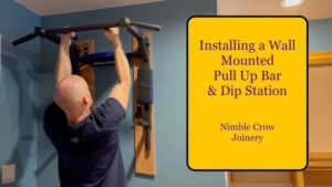 En man griper en installerad pull up-stång som är monterad på en blå vägg.