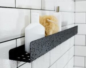 Svart modern duschhylla monterad på vitt kakel i ett badrum.
